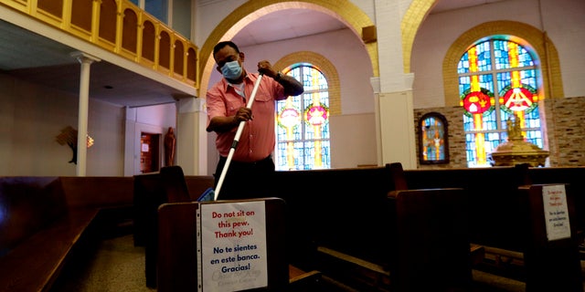 Juan Arriola helps clean and sanitize pews following an in-person Mass at Christ the King Catholic Church in San Antonio, May 19. San Antonio parishes that have been closed due to the COVID-19 pandemic began reopening their doors to in-person services. (AP Photo/Eric Gay)