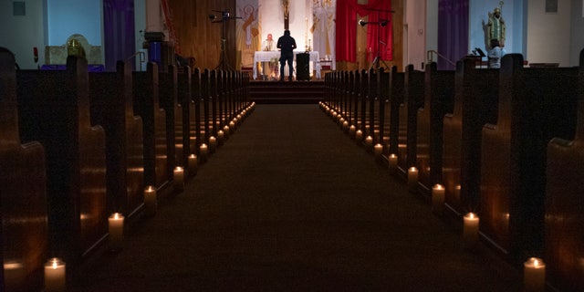 A person films a pastor celebrating Easter Vigil Mass at St. Patrick Church in North Hollywood, Calif on April 11, 2020. The head of the federal Justice Department's Civil Rights Division told Gov. Gavin Newsom Tuesday, May 19, 2020, that his plan to reopen California discriminates against churches. (AP Photo/Damian Dovarganes)