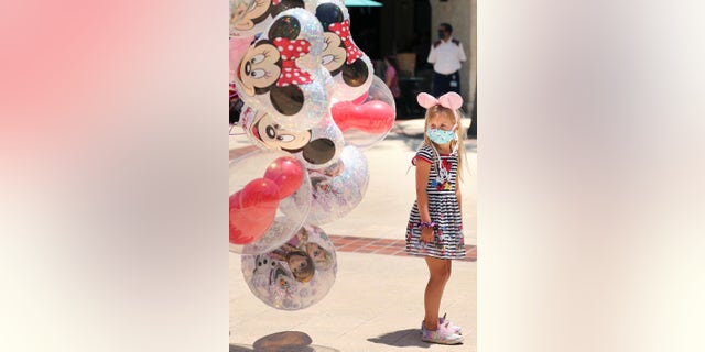 A girl gazes at Mickey Mouse balloons at Disney Springs in Orlando on May 20. Walt Disney World's shopping and dining complex is beginning the first phase of getting back to business. (Stephen M. Dowell/Orlando Sentinel via AP)