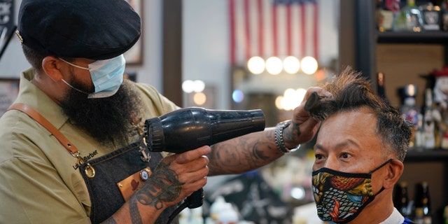 Luis Lopez wears a face mask while giving a hair cut to Alexander Chin at Orange County Barbers Parlor on May 27. (AP Photo/Ashley Landis)