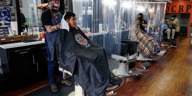 Louie Ruvalcaba gets a hair cut from Saul Arvizu as other customers get their hair cut at Orange County Barbers Parlor on May 27 in Huntington Beach, Calif. (AP Photo/Ashley Landis)