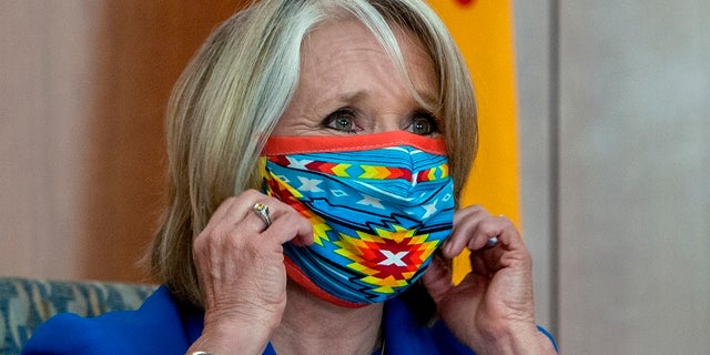 New Mexico Gov. Michelle Lujan Grisham removes her face mask at the start of an update on the COVID-19 outbreak in New Mexico and the State's effort to limit the impact of the disease on residents, during a news conference at the State Capitol on Wednesday. (Eddie Moore/The Albuquerque Journal via AP)