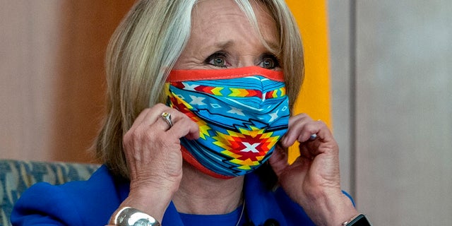 New Mexico Gov. Michelle Lujan Grisham removes her face mask at the start of an update on the COVID-19 outbreak in New Mexico and the State's effort to limit the impact of the disease on residents, during a news conference at the State Capitol on Wednesday. (Eddie Moore/The Albuquerque Journal via AP)