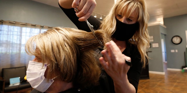 Tisha Fernhoff cuts Lisa Froling's hair at the Beauty Bar Salon in Auburn, Calif. on May 27. Froling was the salon's first client after reopening Wednesday morning. (AP Photo/Rich Pedroncelli)