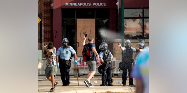 Police spray protesters as demonstrations continue at the Minneapolis 3rd Police Precinct, Wednesday, May 27, 2020, in Minneapolis. The mayor of Minneapolis called for criminal charges against the white police officer seen on video kneeling against the neck of a handcuffed black man who complained that he could not breathe and died in police custody, on Memorial Day. (Carlos Gonzalez/Star Tribune via AP)