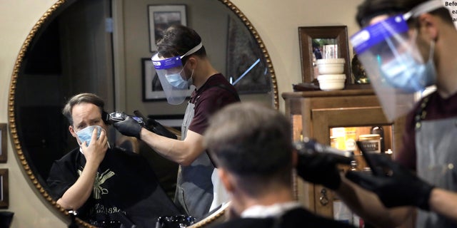 Vin Norton, of Wellesley, Mass., left, gets his hair cut by barber Cristian Lopez, of Sherborn, Mass., at Barber Walter's barbershop, as they both wear masks out of concern for the coronavirus on May 26. (AP Photo/Steven Senne)