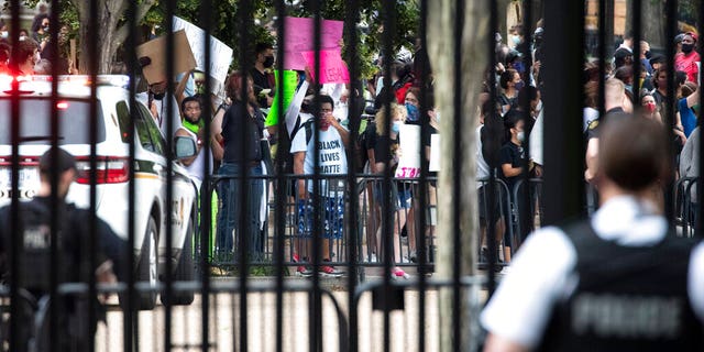A U.S. Secret Service officer stands inside the fence at the White House as demonstrators protest the death of George Floyd, a black man who died in police custody in Minneapolis, Friday, May 29, 2020, in Washington. (AP Photo/Alex Brandon)
