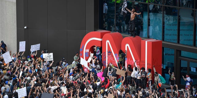 Demonstrators paint on the CNN logo during a protest, Friday, May 29, 2020, in Atlanta, in response to the death of George Floyd in police custody on Memorial Day in Minneapolis. The protest started peacefully earlier in the day before demonstrators clashed with police. (AP Photo/Mike Stewart)