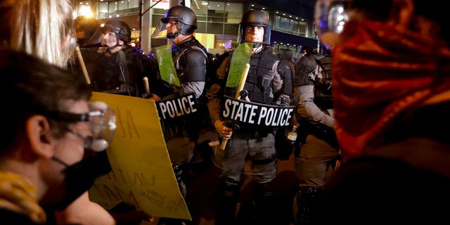 Protesters stand in front of Kentucky State Police officers as they protest the deaths of George Floyd and Breonna Taylor, Friday, May 29, 2020, in Louisville, Ky. Breonna Taylor, a black woman, was fatally shot by police in her home in March.