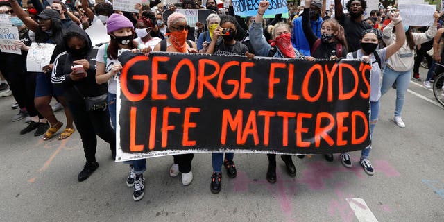 Protesters hold signs as they march during a protest over the death of George Floyd in Chicago, Saturday, May 30, 2020. 
