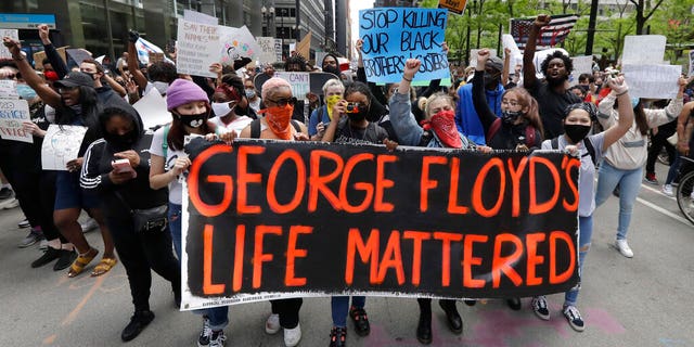 Protesters hold signs as they march during a protest over the death of George Floyd in Chicago, Saturday, May 30, 2020. 