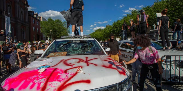 Demonstrators stand on U.S. Secret Service vehicles, one with a broken windshield, near the White House on Saturday, May 30, 2020 (AP Photo/Manuel Balce Ceneta)