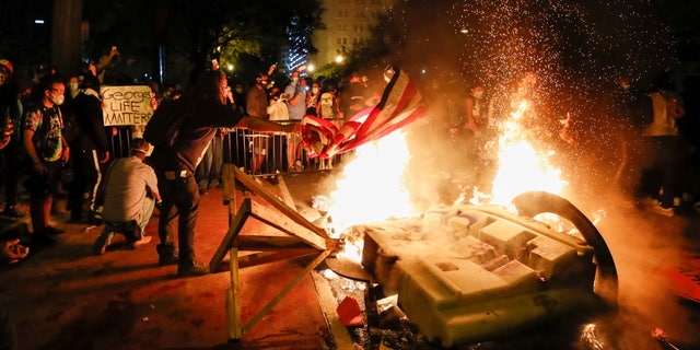 Demonstrators start a fire as they protest the death of George Floyd, Sunday, May 31, 2020, near the White House in Washington.