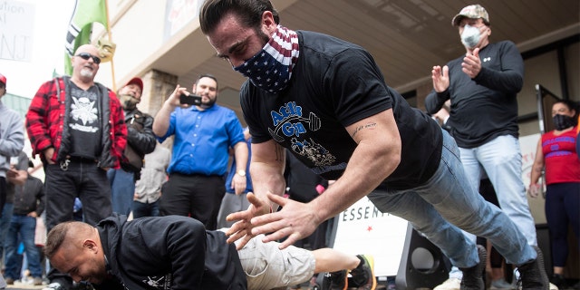 Atilis Gym co-owner Ian Smith does pushups outside the storefront in Bellmawr, N.J., Monday, May 18, 2020. The gym in New Jersey reopened for business early Monday, defying a state order that shut down nonessential businesses to help stem the spread of the coronavirus. (AP Photo/Matt Rourke)