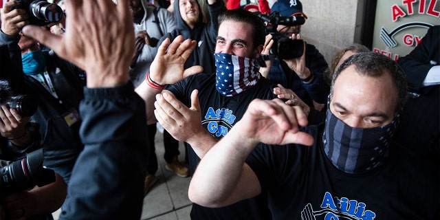 Atilis Gym co-owners Frank Trumbetti, center right, and Ian Smith, center, react after meeting with a police officer outside their gym in Bellmawr, N.J., Monday, May 18, 2020. The gym in New Jersey reopened for business early Monday, defying a state order that shut down nonessential businesses to help stem the spread of the coronavirus. (AP Photo/Matt Rourke)