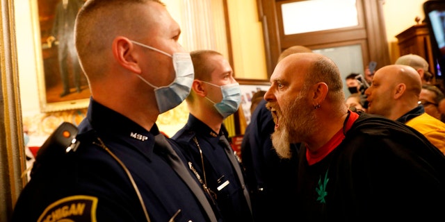 Protestors tried to enter the Michigan House of Representative chamber and were being kept out by the Michigan State Police at the State Capitol in Lansing,  on April 30. The group was upset with Michigan Gov. Gretchen Whitmer's mandatory closure to curtail Covid-19. (JEFF KOWALSKY/AFP via Getty Images)