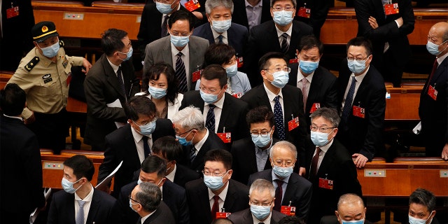 Delegates wearing face masks to protect against the spread of the new coronavirus leave after the opening session of the Chinese People's Political Consultative Conference at the Great Hall of the People in Beijing, Thursday, May 21, 2020. 