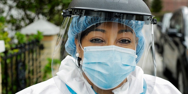 In this Thursday, April 30, 2020, photo, Linda Silva, a nurse's assistant, poses for a portrait in the Queens borough of New York. Silva, who tested positive for COVID-19, returned to work after recovering. It’s been more than a month since she has hugged her two sons or her husband. (AP Photo/Frank Franklin II)