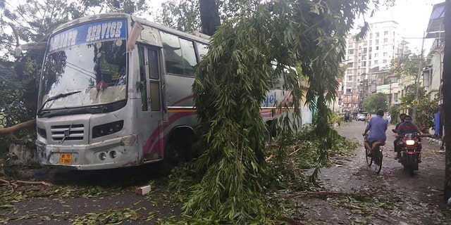 Commuters move past a tree branch precariously hanging after cyclone Amphan hit the region, in Kolkata, India, May 21. A powerful cyclone that slammed into coastal India and Bangladesh has left damage difficult to assess Thursday. (AP Photo/Bikas Das)