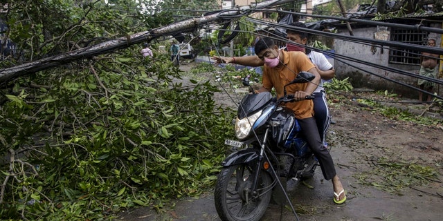 Motorists make their way through damaged cables and a tree branch fallen in the middle of a road after Cyclone Amphan hit the region in Kolkata, India, May 21. (AP Photo/Bikas Das)
