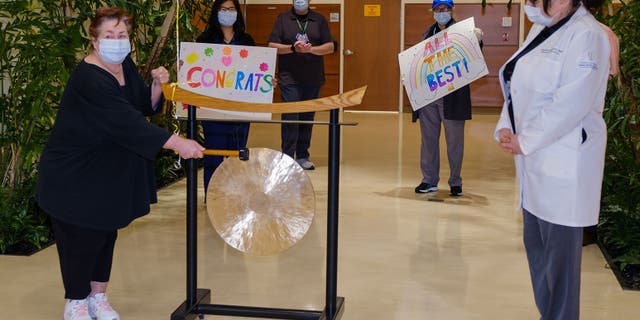 Elizabeth Wyant, 62, of Long Island, rings a gong to celebrate the end of her radiation treatments.