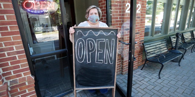 Mary Spoto, general manager of Madison Chop House Grille, places a sign outside the restaurant as she and her staff prepare to shift from take out only to dine-in service Monday, April 27, 2020, in Madison, Ga. (Associated Press)