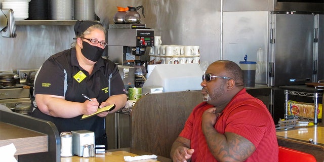 Corey Brooks, right, orders food at a Waffle House restaurant in Savannah, Georgia, on Monday, April 27, 2020. Restaurants statewide were allowed to resume dine-in service with restrictions after a month of being limited to takeout orders because of the coronavirus.