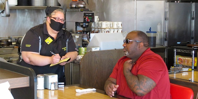 Corey Brooks, right, orders food at a Waffle House restaurant in Savannah, Georgia, on Monday, April 27, 2020. Restaurants statewide were allowed to resume dine-in service with restrictions after a month of being limited to takeout orders because of the coronavirus.