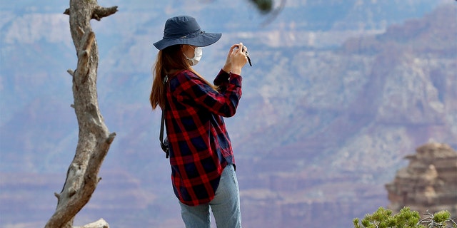 A visitor takes a photo at the Grand Canyon Friday, May 15, 2020, in Grand Canyon, Ariz. Tourists are once again roaming portions of  Grand Canyon National Park when it partially reopened Friday morning, despite objections that the action could exacerbate the coronavirus pandemic. (AP Photo/Matt York)