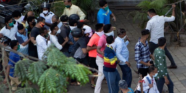A police officer with a baton handles crowd control outside a liquor store in Mumbai Monday. (AP)