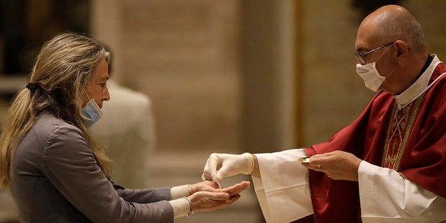 El padre José María Galván, con guantes para evitar la propagación de COVID-19, coloca al anfitrión en manos de un feligrés durante la misa de la mañana en la Iglesia de San Eugenio, en Roma, el lunes 18 de mayo de 2020. Italia levantó parcialmente las restricciones de bloqueo Lunes después de un bloqueo de dos meses por coronavirus.  (Foto AP / Alessandra Tarantino)