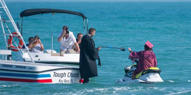 Principal Tom Rompella hands out diplomas at a Jet Ski graduation for graduating seniors at Somerset Island Prep in Key West.