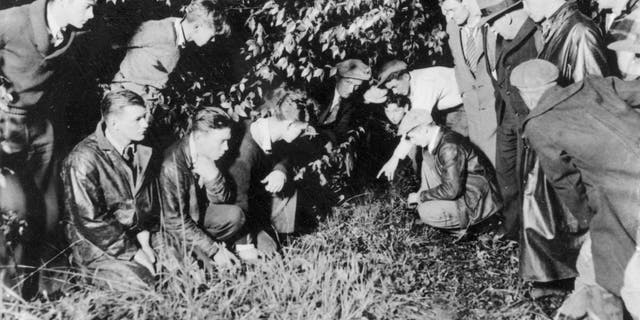 Newsmen and spectators are watching as a young man points to the spot where the body of 19-month-old baby Charles A. Lindbergh Jr., was found in a shallow grave, near Mount Rose, N.J., on May 12, 1932. The infant son of world-famed aviator Charles Lindbergh was kidnapped on March 1, 1932, and found dead today, only four-and-a-half miles away from the Lindbergh estate. (AP Photo)