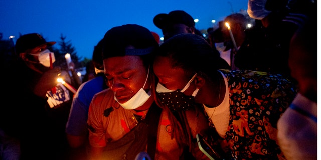 Maalik Mitchell, center left, shedding tears as he said goodbye to his father, Calvin Munerlyn, during a vigil Sunday in Flint, Mich. (Jake May/The Flint Journal via AP)