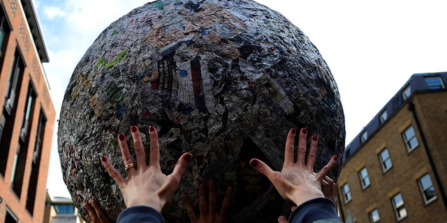 Members of the public hold aloft a giant ball of newspapers as it is rolled through the streets in London May 23, 2009. The sculpture by Italian artist Michelangelo Pistoletto recreated his seminal action "Walking Sculpture", which was first performed on the streets of Turin in Italy in 1966. (REUTERS/Kieran Doherty) 