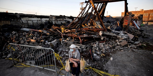 Sandra King, 70, waits for her granddaughter near the remains of AutoZone across from the Minneapolis 3rd Police Precinct in in Minneapolis on Thursday, May 28, 2020. King, who lives in the neighborhood was brought to a protest by her granddaughter. (Carlos Gonzalez/Star Tribune via AP)