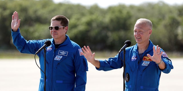 NASA astronauts Bob Behnken, left, and Doug Hurley wave as they leave a news conference after they arrived at the Kennedy Space Center in Cape Canaveral, Fla., Wednesday, May 20, 2020.