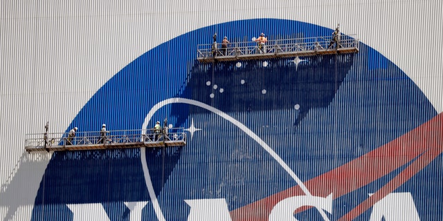 Workers near the top of the 526 ft. Vehicle Assembly Building at the Kennedy Space Center spruce up the NASA logo standing on scaffolds in Cape Canaveral, Fla., Wednesday, May 20, 2020.