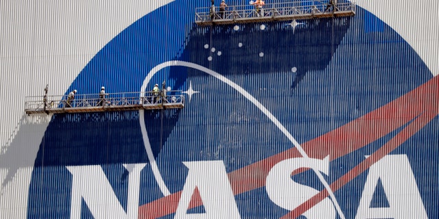 Métis - Workers near the top of the 526 ft. Vehicle Assembly Building at the Kennedy Space Center spruce up the NASA logo standing on scaffolds in Merritt Island, Fla., Wednesday, May 20, 2020.
