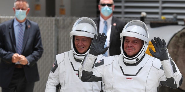 NASA astronauts Bob Behnken (R) and Doug Hurley (L) walk out of the Operations and Checkout Building on their way to the SpaceX Falcon 9 rocket with the Crew Dragon spacecraft on launch pad 39A at the Kennedy Space Center on May 27, 2020 in Cape Canaveral, Florida.