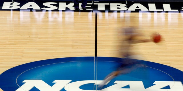 FILE - In this March 14, 2012, file photo, a player runs across the NCAA logo during practice in Pittsburgh before an NCAA tournament college basketball game.