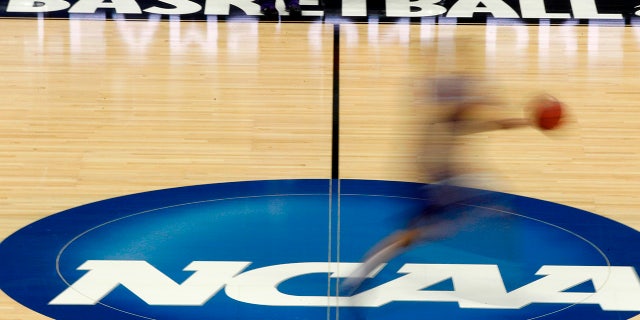 FILE - In this March 14, 2012, file photo, a player runs across the NCAA logo during practice in Pittsburgh before an NCAA tournament college basketball game.