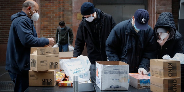 In this Friday, April 24, 2020, photo, workers prepare bags of donated food for people in need through the Coalition for the Homeless organization at St. Bartholomew's Episcopal Church in New York. (AP Photo/John Minchillo)