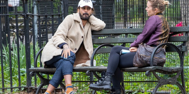 In this Monday, May 11, 2020 photo, a couple, not wearing face masks, sit at a distance from each other on a park bench in Tompkins Square Park in New York. New York's governor has ordered masks for anyone out in public who can't stay at least six feet away from other people. Yet, while the rule is clear, New Yorkers have adopted their own interpretation of exactly when masks are required, especially outdoors. (AP Photo/Mary Altaffer)