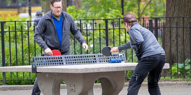 In this Monday, May 11, 2020 photo, men play ping pong without face masks at Tompkins Square Park in New York. New York's governor has ordered masks for anyone out in public who can't stay at least six feet away from other people. Yet, while the rule is clear, New Yorkers have adopted their own interpretation of exactly when masks are required, especially outdoors. (AP Photo/Mary Altaffer)