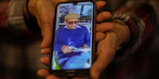 In this Monday, May 18, 2020 photo, Elena Valero shows a picture of her father Alonso Valero, 96, in Madrid, Spain. Alonso Valero was one of the residents at the Usera Center for the Elderly, who died during the coronavirus outbreak in Spain. (AP Photo/Bernat Armangue)