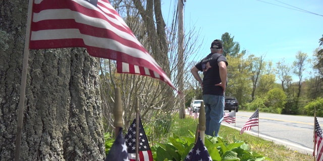 Paul Monti stands by his American flag display at his home in Raynham, Mass.