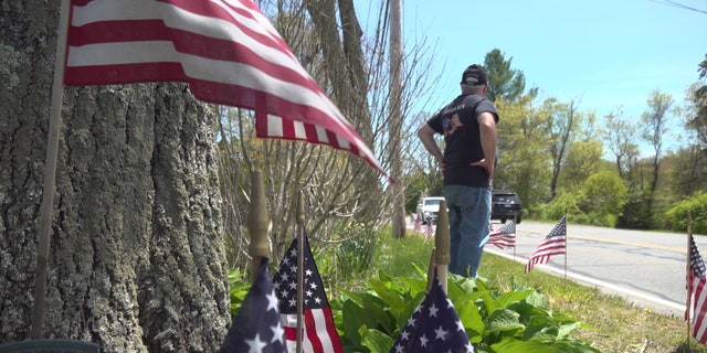 Paul Monti stands by his American flag display at his home in Raynham, Mass.