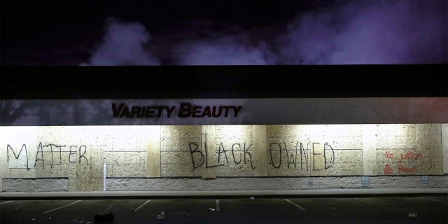 A business labeled "Black Owned" remains untouched by looters, Friday, May 29, 2020, in Minneapolis. Protests continued following the death of George Floyd, who died after being restrained by Minneapolis police officers on Memorial Day. (AP Photo/John Minchillo)
