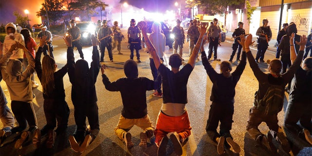 Demonstrators kneel before police Saturday, May 30, 2020, in Minneapolis. Protests continued following the death of George Floyd, who died after being restrained by Minneapolis police officers on Memorial Day.